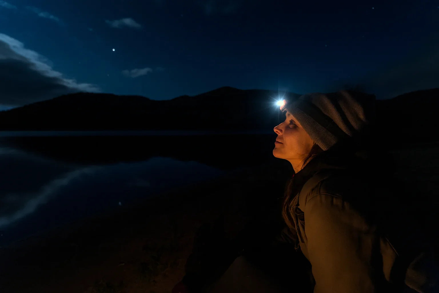 Femme portant une lampe frontale led en pleine nuit en randonnée.